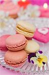 Vanilla, strawberry and raspberry macaroons on a glass plate with a pansy