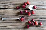 Cranberries and two spoons on a wooden surface