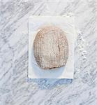 A loaf of bread on paper, on a marble surface, dusted with flour