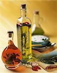 Flavoured oil and vinegar in bottles; a bowl of herb sauce in the background