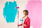 Studio Shot of Young Woman Holding Paint Rollers, Deciding Between Paint Colours