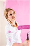 Studio Shot of Young Woman Painting Wall Pink