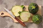 Overhead View of Round Zucchini on Cutting Board with Knife, One Cut in Half