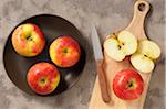 Overhead View of Apples on Plate and Cutting Board with Knife, One Cut in Half