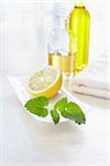 Fresh lemon balm, a lemon and towel with bottles of aromatic oil for aromatherapy