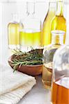 Sprig of rosemary in a bowl, fresh herbs, a towel and bottles of essential oil for aromatherapy