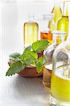 Sprig of lemon balm in a bowl, herbs and bottles of essential oil