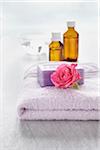 Rose and bath products like towel, soap and bottles of essential oil for aromatherapy and wellness