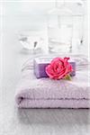 Rose and bath products like towel, soap and bottles of essential oil for aromatherapy and wellness