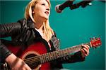 Woman Playing Acoustic Guitar and Singing in Studio