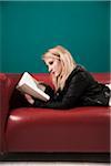 Woman Lying on Sofa and Reading a Book