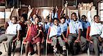 African school pupils smiling at camera with their hands in the air