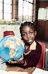 Female African student holds a globe of the earth, while smiling at camera