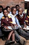 Group of African children eating lunch together outside