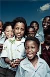 Group of African school children standing outside, smiling at camera