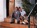 Girl and boy (6-9) sitting on steps, smiling, portrait