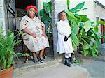 Old woman sitting in front of her township house with her granddaughter, Alexandra, Gauteng, South Africa