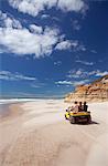 South America, Brazil, Ceara, Morro Branco, tourists riding along a long sandy beach next to the sandstone cliffs near Morro Branco