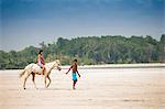 South America, Brazil, Para, Amazon, Marajo island, local man leads a girl on horseback across a beach near Soure