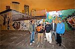 South America, Brazil, Sao Paulo, Vila Madalena, musicians in the Beco do Batman   an alley covered in Brazilian graffiti under the yellow neon glow of the Sao Paulo sky