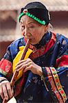 China, Yunnan, Liuyi. Lady playng a Chinese flute in the village of Liuyi.