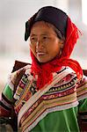 China, Yunnan, Xinjie. A lady from the Hani ethnic minority group at Xinjie market, with a woven rush rain protector strapped to her back.