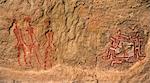 Chad, Gaora Hallagana, Ennedi, Sahara. An ancient rock painting of three human figures, two holding lances, and a bichrome geometric design.