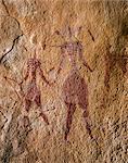 Chad, Elikeo, Ennedi, Sahara. Two bichrome figures with decorated bodies and headdresses, one carrying a bow.