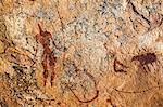 Chad, Guili Dweli, Ennedi, Sahara. A rock painting of two men and a cow, one man with a long curved stick or lance, the other running.