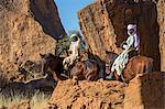 Chad, Barakatra, Ennedi, Sahara. Two young Tubu boys ride their horses among large boulders.