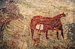 Chad, Terkei West, Ennedi, Sahara.  An ancient rock painting of a human figure with a large spear beneath a Bichrome cow.