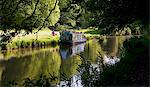 UK, Berkshire. A family have a picnic on the banks of a canal, beside their canal boat.