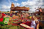 UK, Wiltshire. Little girl enjoying a carousel ride at a traditional steamfair.