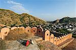 India, Rajasthan, Jaipur, Amber. A village woman gathers fodder on the crenellated walls surrounding Amber Fort.