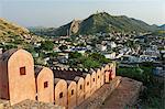 India, Rajasthan, Jaipur, Amber. A village woman carries fodder gathered by the crenellated walls surrounding Amber Fort.