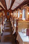 South America, Peru, Cusco, Sacred Valley. The dining car with tables set for dinner on the Orient Express Hiram Bingham train which runs between Cusco and Machu Picchu via Ollantaytambo