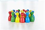 Huddle of multi-colored playing pieces standing together in a group like people