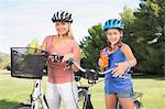 Mother and daughter holding water bottles on bikes