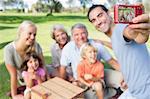 Father taking a photo of family in the park