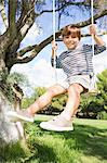 Happy boy on swing hanging from tree