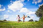 Brother and sister holding hands and playing with a kite