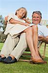 Older woman sitting on lap of smiling partner sitting in deck chair
