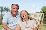 Couple laughing together with woman sitting in deck chair