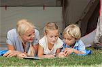 Mother and children reading on a sleeping bag