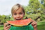 Cute blonde boy eating watermelon