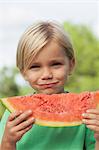 Cute smiling boy eating watermelon
