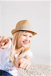 Portrait of Girl wearing Hat and Pointing at Camera in Studio