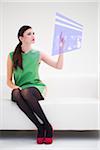 Young Businesswoman Sitting on Sofa using Digital Display, Studio Shot on White Background