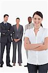 Businesswoman with arms folded and three colleagues behind her against a white background