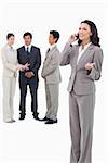 Saleswoman talking on cellphone with colleagues behind her against a white background